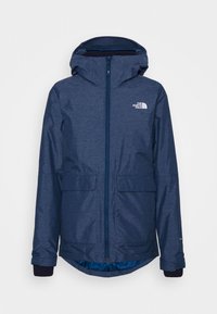Veste imperméable bleu marine avec fermeture éclair à l'avant, capuche réglable, deux poches avant et poignets doublés en polaire. Logo visible sur la poitrine.