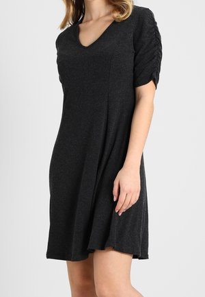 Zwarte, knie-lange jurk met een V-hals, korte gerimpelde mouwen, gemaakt van zachte stof. Heeft een losse, vloeiende silhouet.