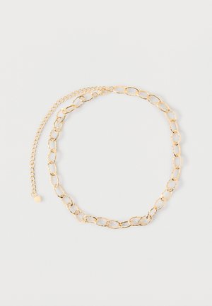 Collar de cadena de oro con eslabones ovalados alargados y una cadena de extensión ajustable, mostrado sobre un fondo liso y claro.