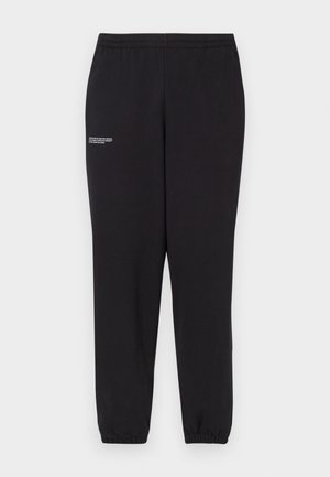 Black sweatpants with elastic waistband and cuffs. Features a small white text detail on one leg. Made from soft, stretchable fabric.