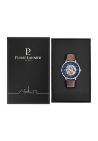 Montre Pierre Lannier avec un cadran bleu, design squelettique, chiffres romains, boîtier argenté et bracelet en cuir marron, présentée dans une boîte noire.