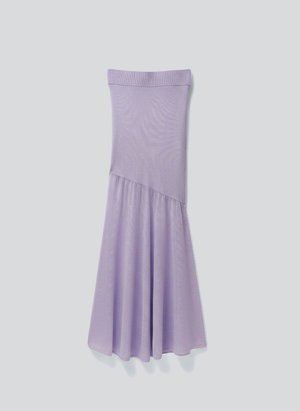Λιλά ασύμμετρη φούστα με εφαρμοστή ριμπ ύφανση στο πάνω μέρος και φαρδιά, ρέουσα κάτω φούστα, σε απλό φωτεινό γκρι φόντο.