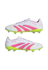Witte voetbalschoenen met roze accenten, groene zool en getextureerde bovenkant. Beschikt over zes doorzichtige noppen en contrasterende strepen voor verbeterde grip.