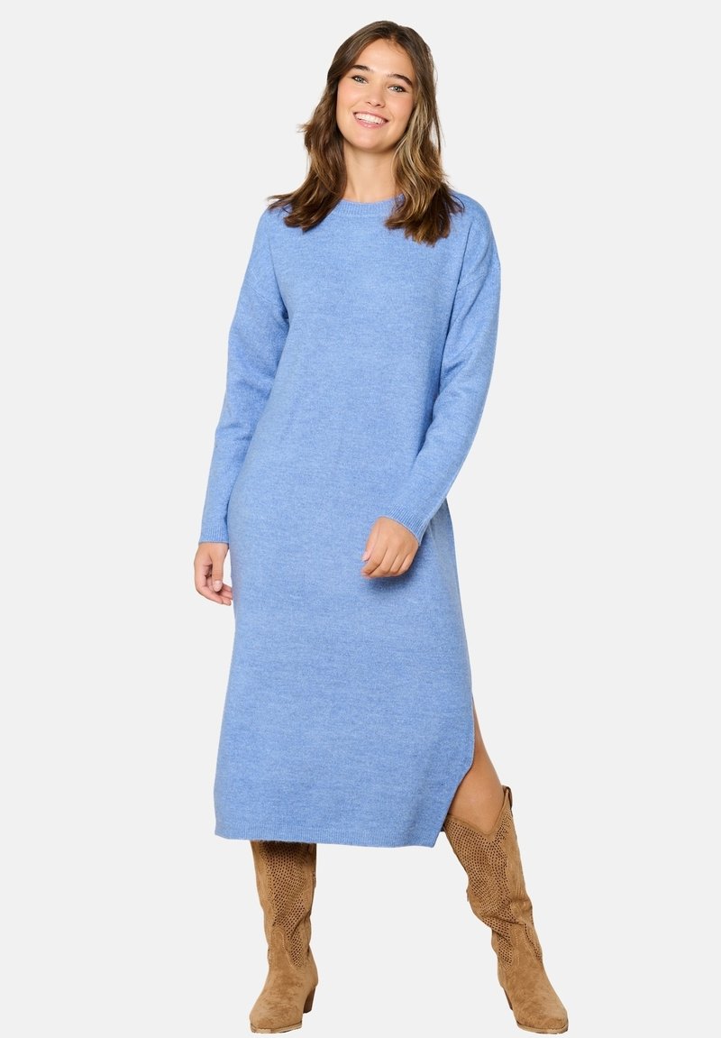 Abito blu a maglia con maniche lunghe e scollatura rotonda, caratterizzato da uno spacco laterale, abbinato a stivali di camoscio color nocciola al ginocchio.