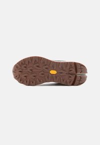 Gumová podrážka turistických bot s hlubokým vzorem, hnědá barva, obsahuje logo Vibram, navržena pro trakci na drsném terénu.
