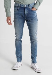 Ljusblå slim-fit jeans i denim, med blekta detaljer och femfickorsdesign. I kombination med vita sneakers.