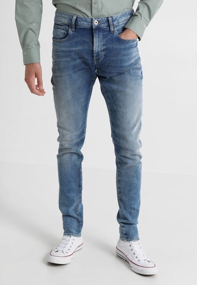 Ljusblå slim-fit jeans i denim, med blekta detaljer och femfickorsdesign. I kombination med vita sneakers.