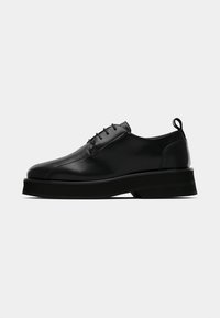 Scarpe in pelle nera con finitura liscia, design con lacci, punta leggermente arrotondata, suola platform spessa e linguetta sul tallone.