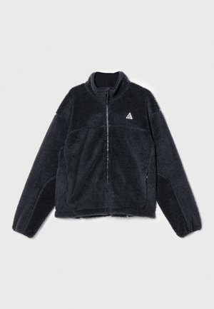 Chaqueta de forro polar gris oscuro con cuello alto, cremallera frontal completa, dos bolsillos laterales y un pequeño detalle de logo en el pecho.