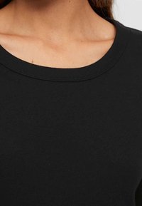 Zwarte katoenen shirt met een ronde hals, met een gladde textuur en nette randen. Het ontwerp heeft een simpele, klassieke stijl.