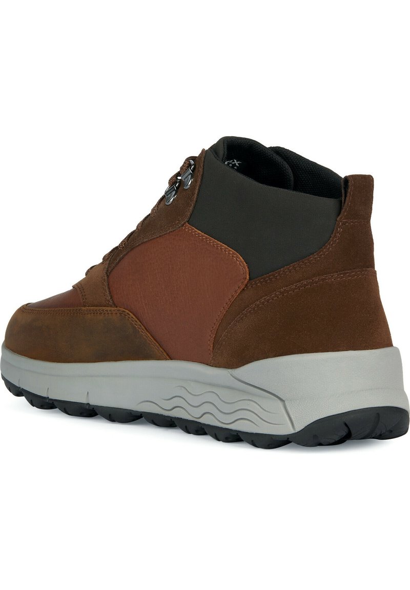 Sneaker mid-top in suede e pelle marrone con suola in gomma grigia, caratterizzato da un design con lacci, dettagli laterali in rilievo e colletto imbottito per un maggiore supporto.