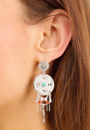 Boucles d'oreilles en argent avec un design en filigrane complexe, accents en turquoise et chaînes tombantes avec des perles rouges, suspendues à un sommet rond.