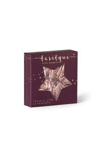 Scrunchie di seta di lusso di colore rosa chiaro, confezionato in una scatola viola scuro con un'apertura a forma di stella, testo dorato e accenti decorativi a forma di stella.