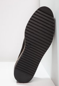 Černá gumová podrážka s horizontálními žebry a zaoblenou špičkou. Velikost 37 je označena uvnitř kruhu. Texturovaný povrch pro lepší přilnavost.