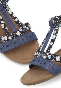 Blaue Sandalen mit Blumenmuster verfügen über ausgeschnittene Akzente, mehrere Riemen und eine strukturierte, neutralfarbene Fußsohle. Flaches Sohlen-Design.