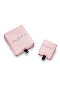 Rozā dāvanas kastītes ar zelta sirds rakstu; viena lielāka ar melnu lentu, un blakus mazāka, abām ar logo "GLANZSTÜCKE MÜNCHEN."