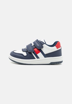 Zapatilla infantil en azul marino, blanco y rojo con dos velcros y suela acolchada, vista de perfil sobre un fondo blanco.