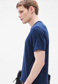 Κοντομάνικο μπλε ναυτικό t-shirt από ελαφρύ ύφασμα, με στρογγυλή λαιμόκοψη και διακριτικό λογότυπο της μάρκας στο στήθος. Λείο ύφασμα.