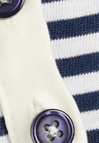Laivastonsininen ja valkoinen raidallinen kangas, jossa on sileä rakenne. Kankaassa on valkoinen nappilista ja nelireikäinen violetti nappi.