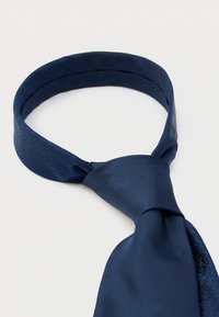 Marineblaue Krawatte mit glatter Textur und einem dezenten Musterakzent auf einem breiteren Abschnitt, am unteren Ende zu einem klassischen Knoten gebunden.