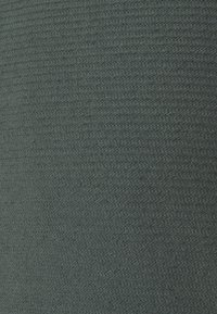 Teksturowana tkanina w ciemnozielonym kolorze, z żebrowanym wzorem. Powierzchnia wydaje się miękka, z jednolitym splotem na całej powierzchni.