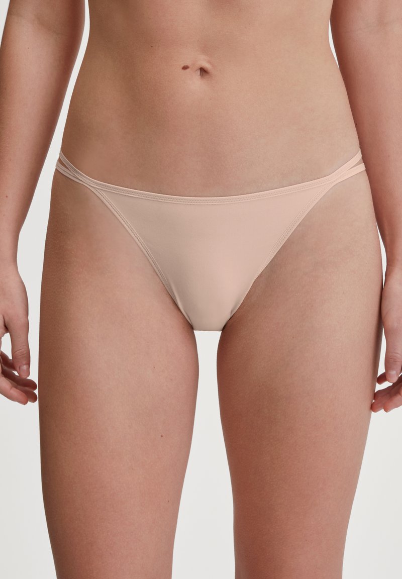 Lichtroze, naadloze bikini briefs met een dunne elastische tailleband en minimale bedekking. Gloves textuur, eenvoudig ontwerp, geen zichtbare patronen of hardware.