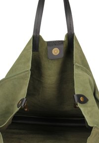 Groene suede totebag met zwarte leren handvatten, metalen drukknoopsluiting en een zachte binnenkant. Voorzien van gestikte details en leren accenten.