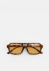 Lunettes de soleil écaille de tortue avec une forme rectangulaire, dotées de verres teintés bruns et d'une monture épaisse. Remarquables pour leur design minimaliste.