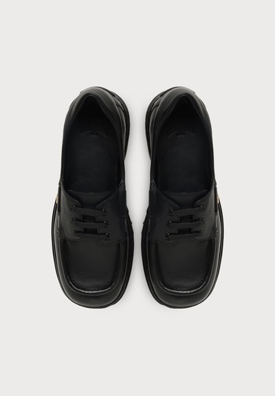 Paire de chaussures habillées en cuir noir à lacets vue de dessus sur un fond clair uni.