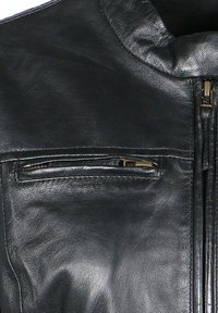 Giacca in pelle nera con chiusura con zip, colletto alto e una piccola tasca con zip sul petto con hardware dorato. Texture liscia.