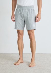 Grå treningsshorts laget av myk stoff, med elastisk midje og en liten logo-patch på venstre ben.
