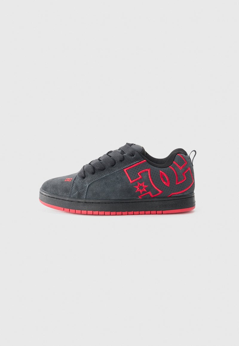 Sorte sneakers i ruskind med røde accenter, der har et fremtrædende logo, runde snørebånd og en tekstureret gummisål for godt greb.