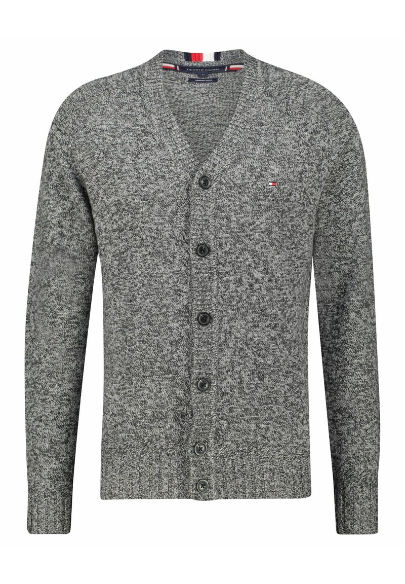 Szary kardigan z teksturowanym wzorem na dżerseju, w dekolcie w serek, zapinany na sześć czarnych guzików. Posiada czerwone i niebieskie paski akcentowe na dekolcie.