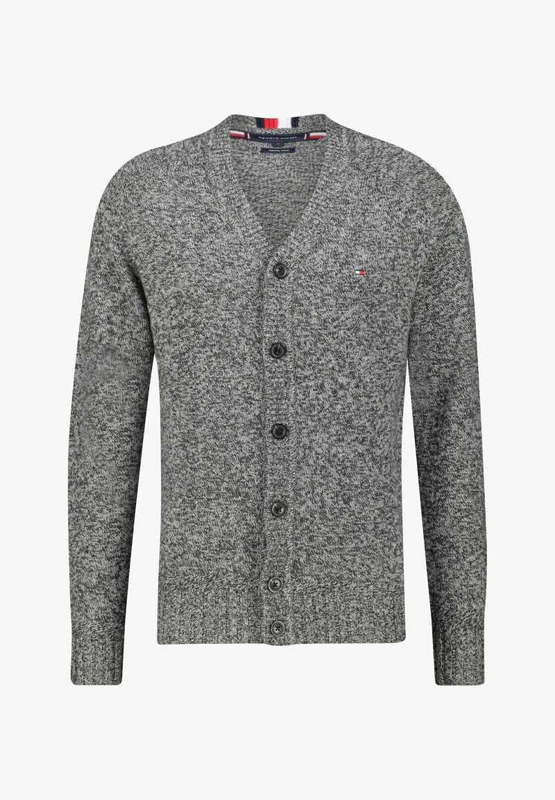 Szary kardigan z teksturowanym wzorem na dżerseju, w dekolcie w serek, zapinany na sześć czarnych guzików. Posiada czerwone i niebieskie paski akcentowe na dekolcie.