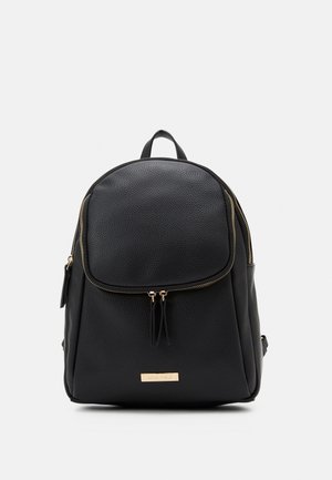 Sac à dos en cuir texturé noir avec poche avant zippée, détails de fermeture éclair dorés et petite plaque de marque rectangulaire dorée à la base.