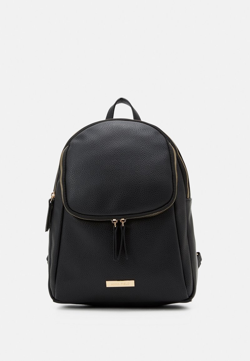 Sac à dos en cuir texturé noir avec poche avant zippée, détails de fermeture éclair dorés et petite plaque de marque rectangulaire dorée à la base.