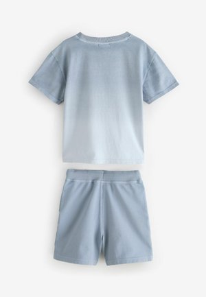 Šviesiai mėlyna medvilninė marškinėliai su trumpomis rankovėmis ir apykakle, derinami su tokios pat spalvos lengvais šortais su elastinga juosmens juosta.