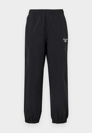 Pantalon noir à taille élastique avec des poignets élastiques et un petit logo Carhartt blanc sur la partie supérieure de la cuisse gauche.