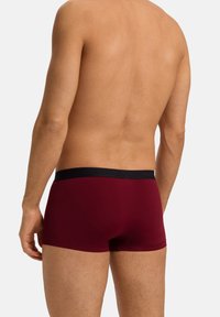 Boxer da uomo color mogano con cintura elastica nera caratterizzata da un branding discreto. Tessuto liscio con un design aderente, che evidenza un taglio moderno.