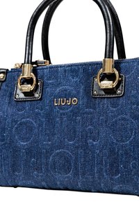 Sac en denim avec une texture bleu foncé, des accessoires en métal doré, des accents en cuir noir et un logo embossé à l'avant. Possède des poignées doubles.