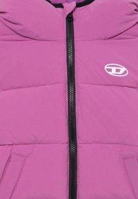 Ljubičasta puffer jakna s crnim zatvaračem i malim bijelim logoom, s kapuljačom i dva prednja džepa. Glatki, lagani materijal.