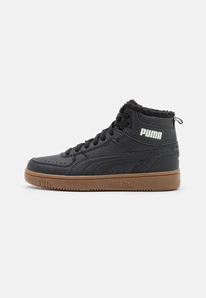 Baskets montantes noires Puma à semelle en gomme, doublure en fourrure, lacets et logo blanc Puma sur le côté et la semelle intermédiaire, visibles de profil droit.