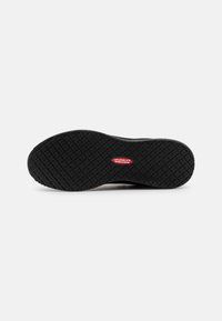 Soletta in gomma nera per sneaker con motivo testurizzato antiscivolo, caratterizzata da un logo rosso contrassegnato "Antiscivolo" sul lato.