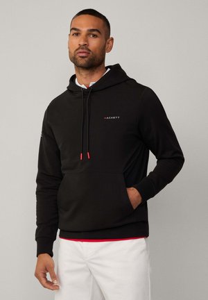 Black hoodie made of soft fabric, featuring a front pocket, adjustable drawstring, and red accent details on drawstrings with a logo.