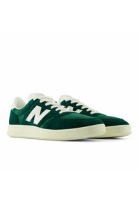 Vihreät mokkanahkaiset lenkkitossut, joissa on valkoinen "N"-logo, rei'itetyt yksityiskohdat, valkoiset nauhat ja vaaleanvärinen kumipohja.