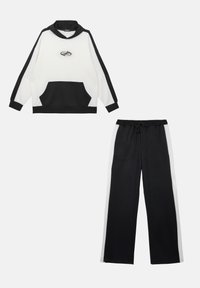 Ensemble de survêtement noir et blanc comprenant un sweat à capuche avec une poche et un pantalon assorti avec des rayures sur les côtés. Fabriqué en tissu doux.