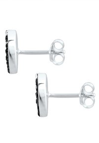 Boucles d'oreilles clous en argent présentant un design circulaire avec un accent en pierre noire. Surface lisse avec un bord texturé pour plus de détails.