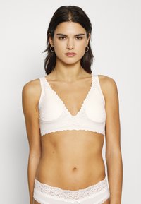 Brassière en dentelle rose clair avec un motif à volants et un décolleté plongeant. Tissu lisse avec un motif floral. Bretelles ajustables pour le confort.