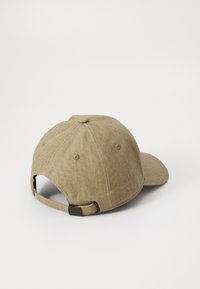 Casquette de baseball kaki en tissu texturé, avec une sangle ajustable à l'arrière et un détail de logo brodé sur le côté. Forme de couronne ronde.
