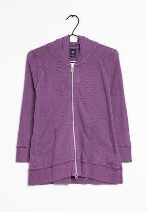 Sudadera con cremallera en color púrpura, con un diseño texturizado, bolsillos delanteros y capucha. Presenta una cremallera plateada y un corte relajado en el dobladillo.